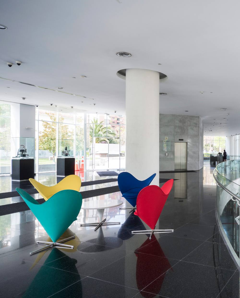 Bci branch lobby with a polished stone floor and sculptural armchairs in green, yellow, blue and red.