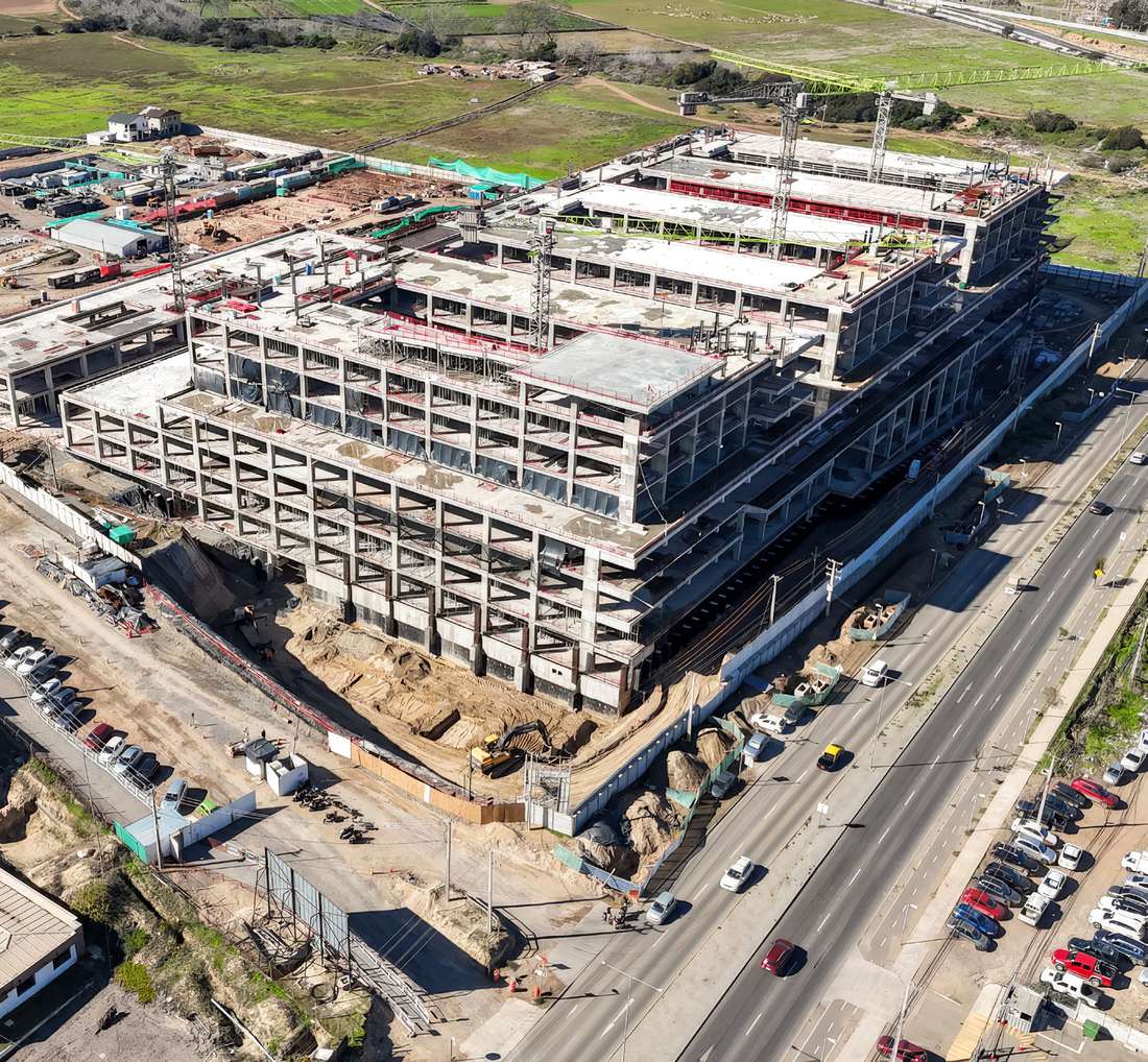 Aerial view of the Coquimbo Hospital construction site, showing exposed concrete floor slabs, tower cranes and the adjacent road.